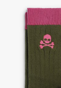 Calcetines de punto en verde oliva con un puño acanalado rosa. Presenta un diseño de calavera y tibias cruzadas en rosa. La textura es suave y de grosor medio.