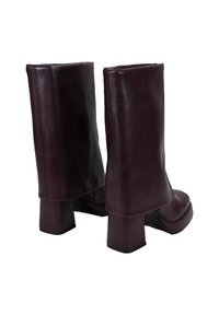 Botines de cuero burdeos con puntera cuadrada y tacón grueso. Textura suave, diseño plegado en la parte superior y estilo minimalista.