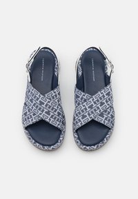 Modré a bílé sandály z vzorované látky s křížovými popruhy a polstrovanou stélkou. Na boku mají stříbrnou sponu.