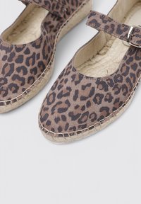 Espadrilles de estampado de leopardo con puntera redondeada, parte superior de tela, tira ajustable y suela envuelta en yute. Superficie texturizada con manchas marrones y negras.
