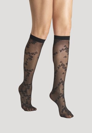 Schwarze, knielange Strümpfe aus durchscheinendem Material, mit einem floralen Muster und einem festen schwarzen Bund oben. Offene Zehen.