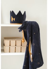 Marineblauwe fluwelen kroon met gele accenten en bijpassende kapmantel met sterrenpatronen, tentoongesteld op een plank bovenop opbergdozen.