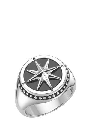 Silberner Ring mit einem erhabenen Kompassrosen-Design auf schwarzem Hintergrund, mit Markierungen für Norden, Osten, Süden und Westen auf dem Rand.