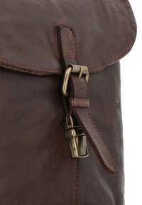 Bruine leren tas met een omvouwbare klep, zichtbare stiksels en een messing sluiting. Gestructureerde oppervlakte met een robuuste uitstraling.