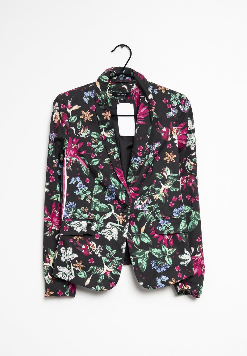 Blazer floral en tissu noir, présentant un mélange de fleurs colorées, deux poches avant et une fermeture à un seul bouton. Suspendu à un crochet noir.