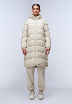 Cappotto puffer beige con cappuccio, caratterizzato da sezioni trapuntate orizzontali, zip frontale e tasche laterali doppie. Abbinato a pantaloni beige a sigaretta e scarpe.