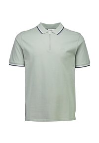 Jasnozielona koszulka polo wykonana z bawełny, z zamkiem błyskawicznym przy kołnierzyku, krótkimi rękawami oraz granatowym wykończeniem na kołnierzyku i rękawach.