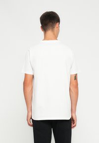 Hvid bomulds-T-shirt med korte ærmer, rund halsudskæring og en afslappet pasform. Har en glat tekstur uden synlige mønstre eller logoer.