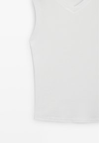 Witte mouwloze top met een V-hals, gemaakt van gladde stof met een aansluitende pasvorm en omzoomde randen. Geen zichtbare patronen of accenten.