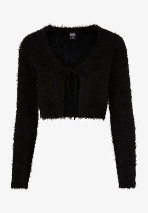 Pull noir court en matériau pelucheux avec des manches longues. Présente un décolleté en V profond et une fermeture à cordon à l'avant.