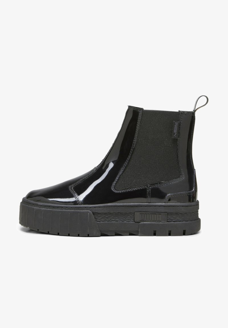 Bottine Chelsea noire brillante avec panneau latéral élastique texturé, semelle épaisse à relief, languette de traction et logo Puma sur la semelle et l'étiquette en tissu.