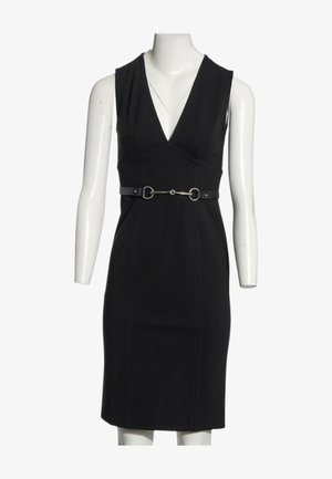 Ärmelloses schwarzes knielanges Kleid mit tiefem V-Ausschnitt und schmalem Gürtel mit silbernem Pferdebit-Detail in der Taille auf einer weißen Schaufensterpuppe.