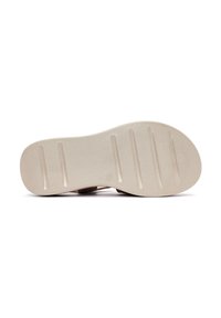 Suola di scarpa beige chiaro con superficie testurizzata, caratterizzata da scanalature orizzontali per migliorare la presa e un tacco arrotondato per stabilità.