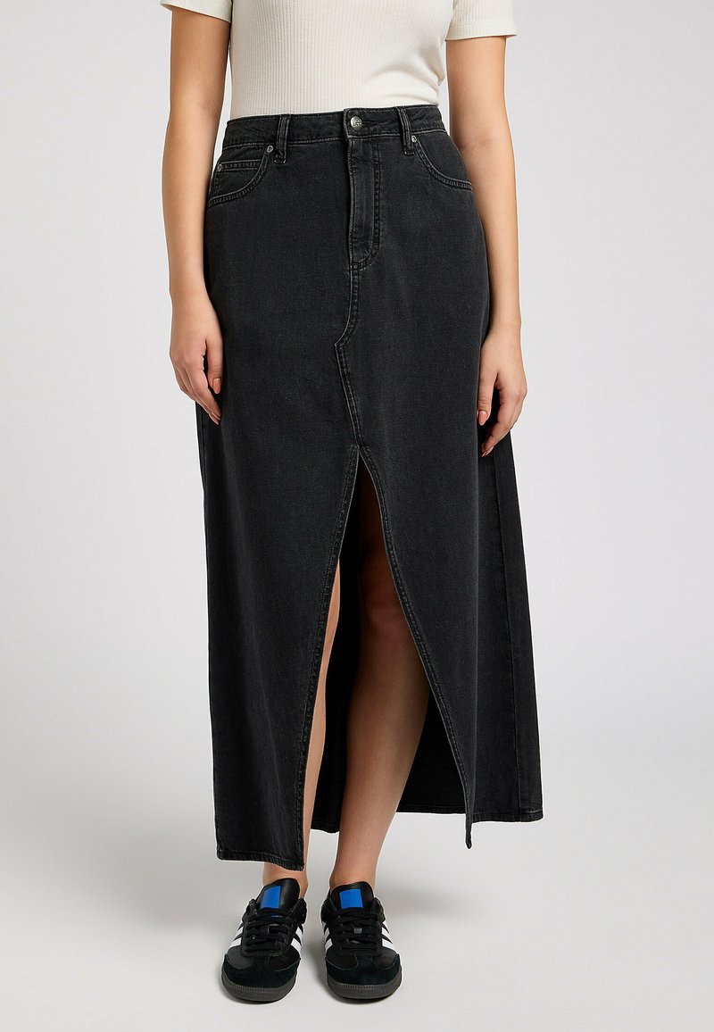 Jupe maxi en jean noir avec une fente à l'avant et une taille haute. Fini avec une fermeture à bouton et des passants de ceinture, associé à des baskets noires.
