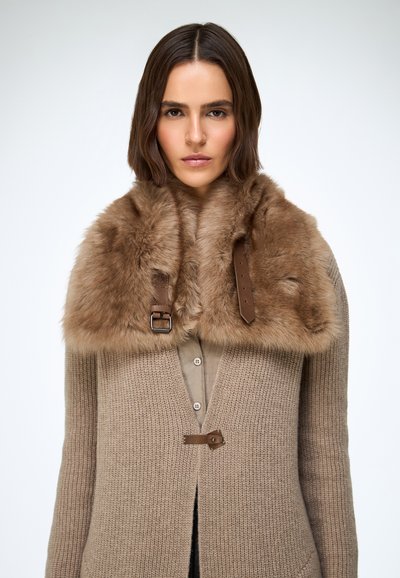 Beżowy dziany kardigan z futrzanym kołnierzem w jasnobrązowym odcieniu, z paskami ze skóry i detalami na klamry, zapinany na guziki, z teksturowaną tkaniną.