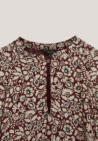 Bordeauxfarbene Bluse mit cremefarbenem Blumenmuster, runder Ausschnitt und Schlitzöffnung vorne, Größe 40 EU, hergestellt in Portugal.