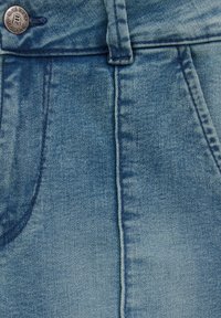 Svijetloplavi traper tkanina, s kopčanjem na gumb, šivenim detaljima i dizajnom s pet džepova. Tekstura je glatka s laganim izbljeđivanjem.