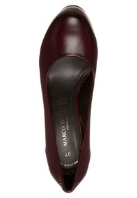 Chaussure en cuir bordeaux avec un bout rond. Texture lisse, côtés bas et détails de couture subtils le long des bords. Logo de la marque visible.