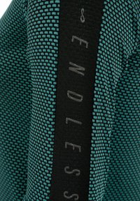 Tessuto teal a motivo con superficie texturizzata, caratterizzato da una banda verticale nera con la scritta "ENDLESS" stampata in grigio chiaro.