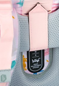 System regulowany z szarym meshem i różowymi paskami. Etykieta pokazuje rozmiar M/S oraz markę baagl. Kolorowy wzór na wewnętrznej tkaninie.