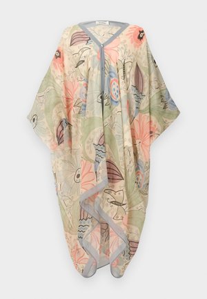 Moteris stovi laikydama ranką ant klubo, vilkėdama permatomą gėlėtą kimono stiliaus kardiganą ir derančias plačias pastelines kelnės.