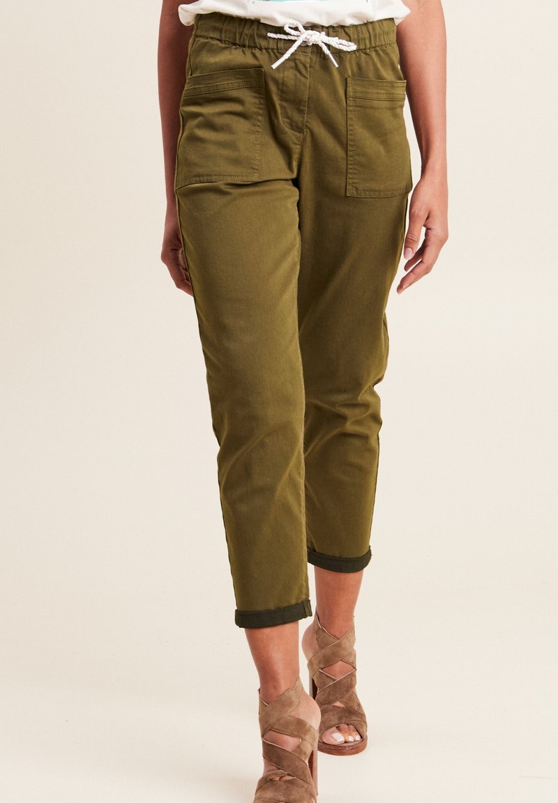 Pantalons en coton mélangé vert olive avec une coupe décontractée, taille élastique, détail de cordon de serrage et deux poches avant, manches retroussées.