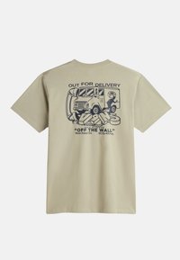 Camiseta beige con un gráfico de un camión de entrega y el texto "EN RUTA DE ENTREGA" en azul oscuro en la parte posterior. Cuello redondo, mangas cortas.