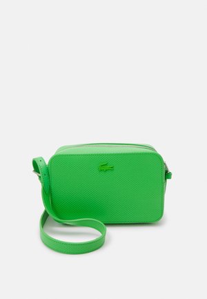 Grüne strukturierte Umhängetasche mit Reißverschluss, verstellbarem Riemen und geprägtem Logodetail auf der Vorderseite. Kompakte rechteckige Form.