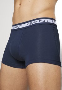 Navy blue cotton boxer shorts with a light blue waistband featuring the brand name "GANT" in bold text. Designed with a snug fit and flat seams.