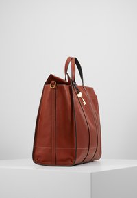 Braune Leder-Tote mit schwarzen Akzenten, verfügt über ein strukturiertes Design, doppelte Tragegriffe und ein goldfarbenes Schlüsselchen, das angebracht ist.