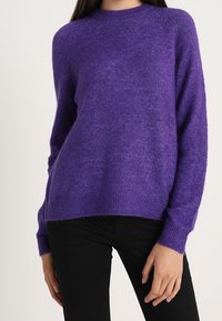 Lila Strickpullover mit langen Ärmeln, Rundhalsausschnitt und weichem Textil. Hat eine lockere Passform mit gerippten Bündchen und Saum.