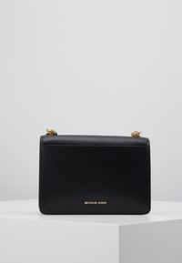 Černá kožená kabelka s hladkou texturou, obdélníkovým tvarem, zlatým kováním a vyraženým logem na přední straně. Odnímatelný řetízkový popruh.