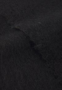 Materiale di feltro nero con una consistenza morbida e fibrosa, che presenta una leggera lucentezza e una superficie irregolare, creando profondità e variazioni nell'aspetto.