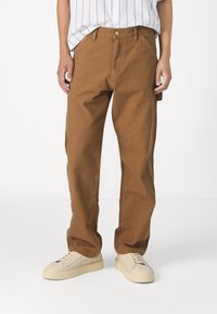 Pantalones de algodón marrón de pierna ancha con una cintura alta, que cuentan con bolsillos frontales, cierre de botón y una textura suave y resistente.