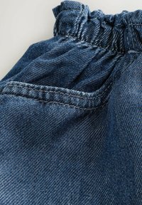 Sötétkék farmeranyag összehúzott rugalmas derékpánttal és kis zsebbel. Texturált felület, kontrasztos varrással.