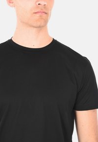 T-shirt nero a maniche corte realizzato in tessuto liscio con scollatura a girocollo classica. Presenta linee pulite e un design semplice.