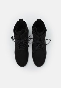 Bottes basses en daim noir à bout rond, avec lacets à l'avant et col rembourré. Texture lisse avec lacets ton sur ton et languette pour un enfilage facile.