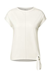 T-shirt blanc à manches courtes, avec des clous décoratifs le long des coutures d'épaule et un détail de nœud noué à l'ourlet. Tissu doux et lisse.