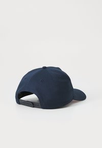 Gorra de béisbol azul marino con visera curva, correa ajustable de tipo snapback, tela suave y un patrón de costura en la corona.