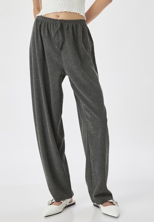 Grijze, gestructureerde, wijde broek met een elastische tailleband en strikdetail, gecombineerd met witte muiltjes met een spitse neus en een gespsluiting.