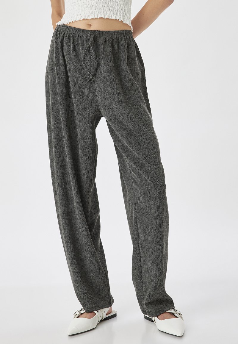 Grijze, gestructureerde, wijde broek met een elastische tailleband en strikdetail, gecombineerd met witte muiltjes met een spitse neus en een gespsluiting.