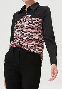 Chemise noire à boutons avec un panneau avant à motif rose et noir ; présente un col et des manches longues, texture lisse.