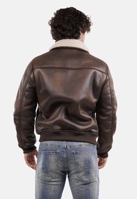 Giacca di pelle marrone con colletto in pelliccia, polsini e fascia in vita a costine, con una superficie liscia e un design aderente.