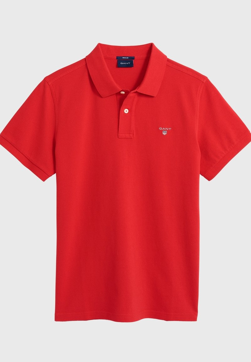 Polo rouge en coton, avec un col classique, des manches courtes et un petit logo brodé sur la poitrine.