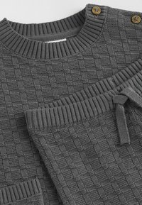 Gray knit sweater and joggers with a textured check pattern, ribbed trims, and two buttons on the shoulder for detail.