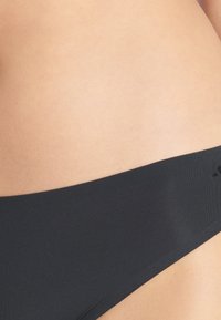 Svart sömlös underkläder med en mjuk elastisk midjeband, med en slät yta och en minimalistisk design. Inga synliga mönster eller hårdvara.