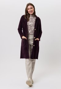 Lange, open voorkant cardigan in diep paars, gemaakt van zacht, pluizig materiaal. Heeft grote knopen, zijzakken en een getextureerde franjeszoom.