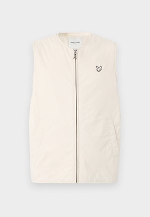 Beige ermeløs vest med glidelås foran, to sidelommer og en liten brodert ørnerlogo på brystet. Glatt stofftekstur.