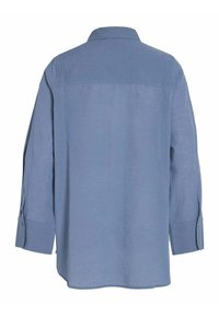 Svijetloplava majica dugih rukava s klasičnim ovratnikom, dugmićima na rukavima i opuštenim krojem. Izrađena od lagane tkanine s glatkom teksturom.