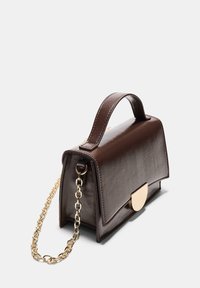 Braune Lederhandtasche mit strukturiertem Design, ausgestattet mit einem goldenen Kettenriemen und einem runden Metallverschluss. Glatte Textur, minimalistische Details.